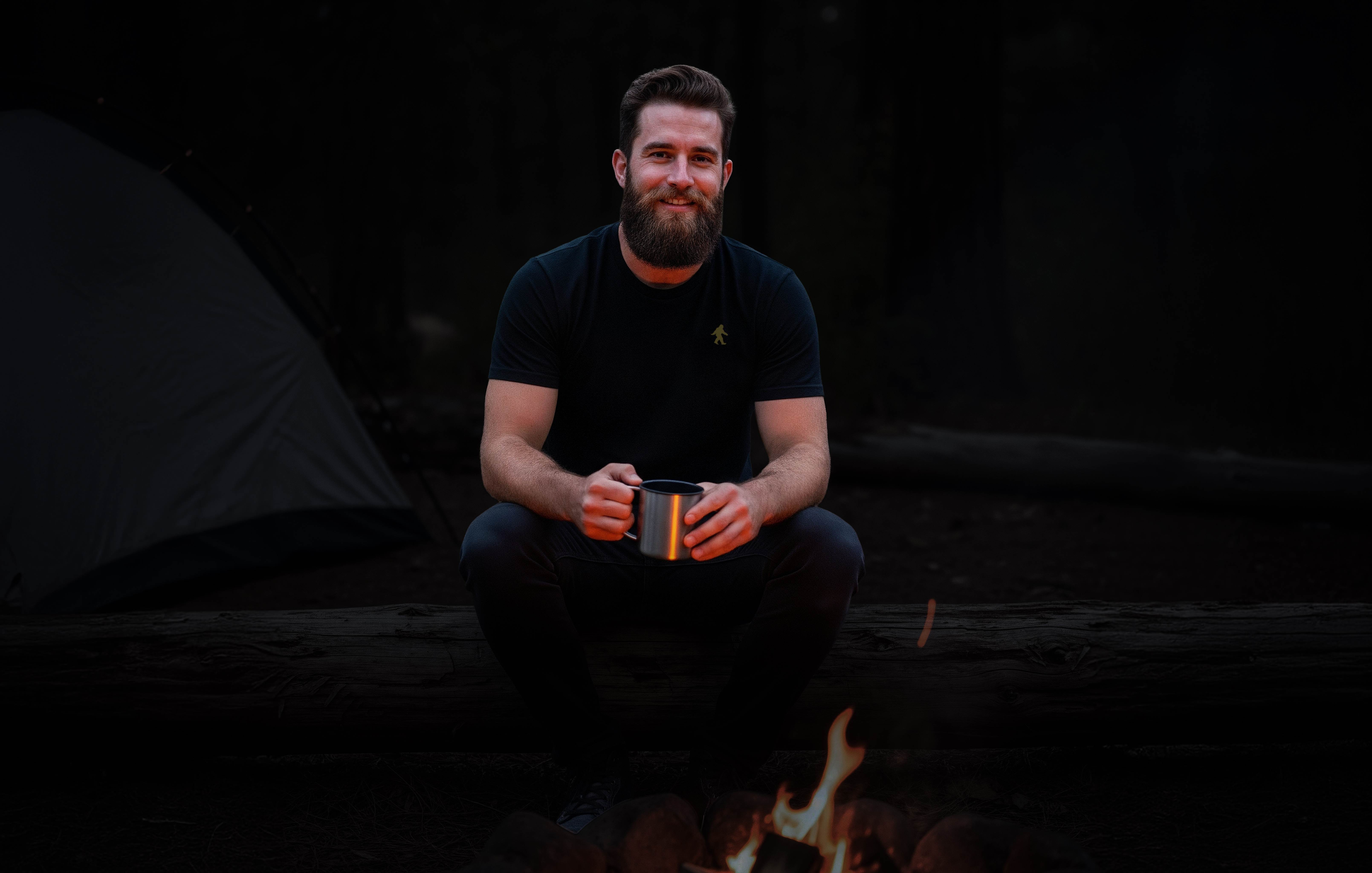 Man in The Real Bigfoot t-shirt by a campfire at night.
